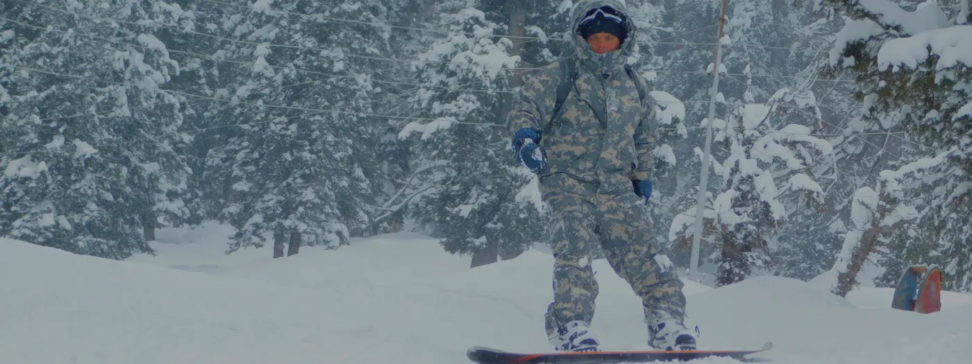 Snowboarder riding through the tree line in Gulmarg